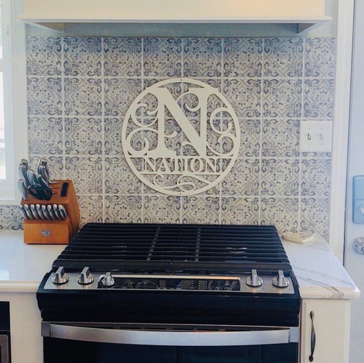 Round metal art wall sign with a full monogram letter with scrolling and a name line underneath the monogram.  The entire design with within the bounds of the circle